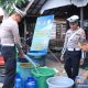 Anggota Satlantas Polres HSU mengisikan bak penampungan air milik warga Desa Pematang Benteng Hilir.