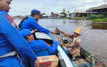 Anggota Sat Polairud Polres HSU membagikan bingkisan sembako kepada warga Desa Paminggir. (Foto : Humas Polres HSU)