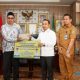 Bupati Tapin, H. Yamani menyerahkan bantuan hibah secara simbolis kepada penerima manfaat. (Foto : Prokopim Tapin)