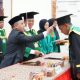 Bupati Tapin H. Yamani melakukan prosesi pemindahan kuncir toga wisudawan STIT Assunniyyah Tambarangan. (Dok. Prokopim Tapin)