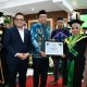 Bupati HSS H Syafrudin Noor menyerahkan piagam kepada mahasiswa IAI Darul Ulum Kandangan yang lulus berprestasi. (Dok. Kominfo HSS)