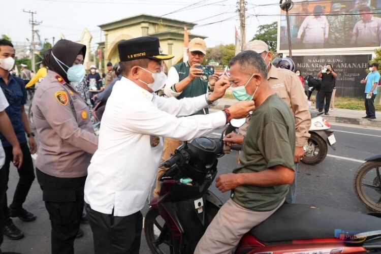 Bupati Kapuas, HM Wiyatno memasangkan masker kepada salah seorang pengguna jalan. (Dok: Istimewa)