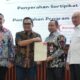 Bupati Tapin H Yamani menerima sertifikat hak pakai atas tanah aset daerah dari Ketua Komisi II DPR RI Rifqinizami Karsayuda. (Dok: Prokopim Tapin)