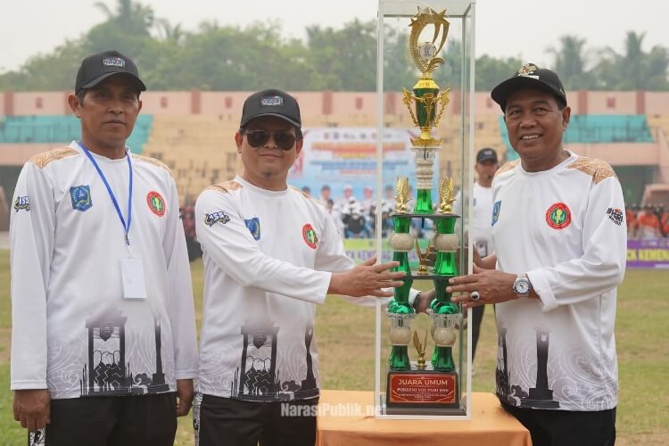 Bupati HSS H Syafrudin Noor menyerahkan trophy bergilir kepada panitia PORSENI VIII PGRI Kabupaten HSS Tahun 2026. (Dok: Istimewa)